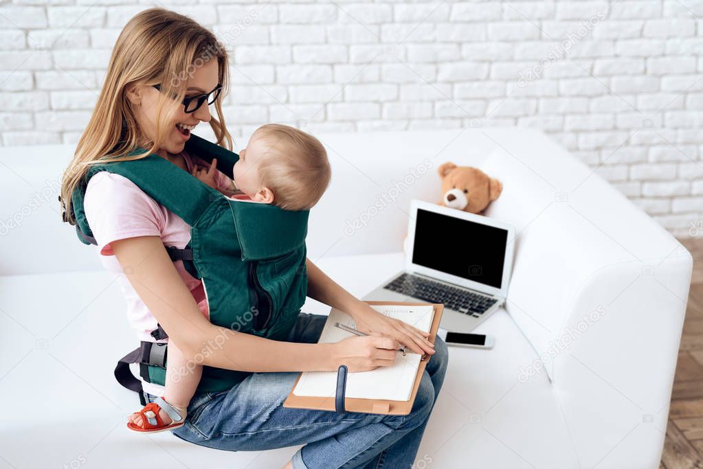 Business woman working with newborn in baby sling