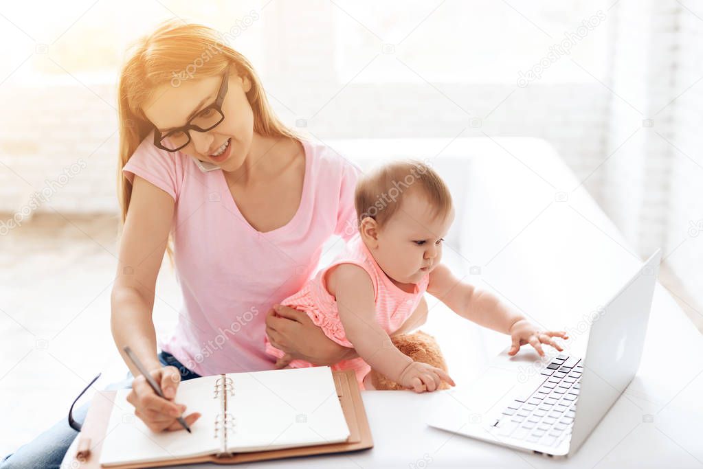 Mother with baby working and using smartphone.