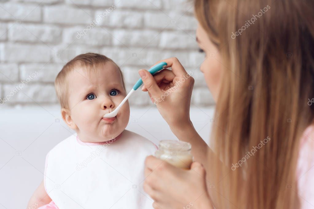 Young mother with spoon feeding little baby.