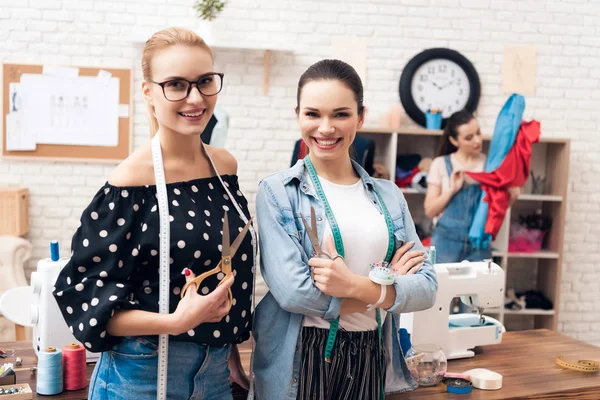 Three girls at garment factory. Two of them holding pairs of scissors.