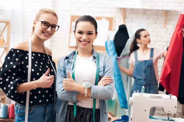 Three girls at garment factory. They are giving thumbs up finished new dress. — Stock Photo, Image