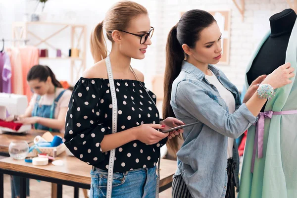 Trois filles à l'usine de vêtements. Ils cherchent à dessiner une nouvelle robe . — Photo