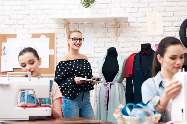 Drie vrouwen in kledingstuk fabriek. Ze zitten achter de naaimachines. — Stockfoto