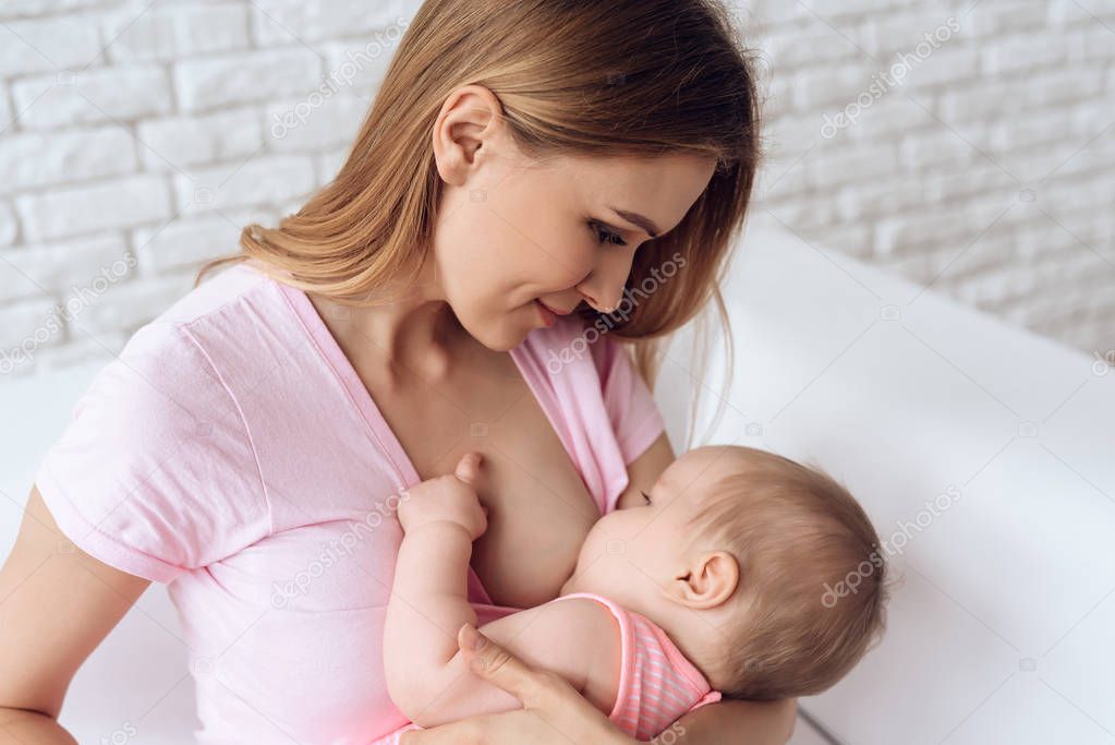 Young mother feeding breast baby.