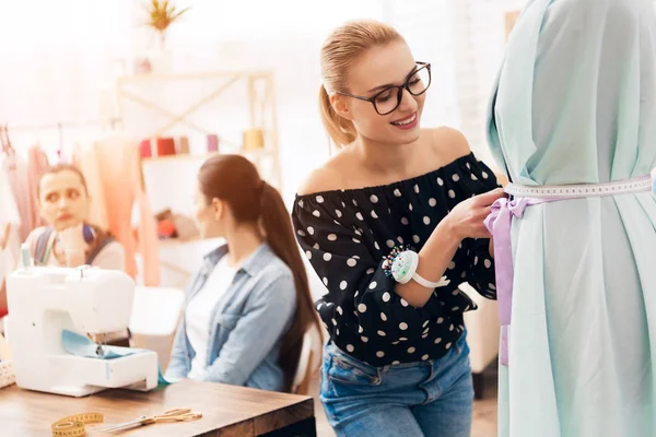 Trois femmes à l'usine de vêtements. Ils sont assis derrière des machines à coudre et prennent des mesures de nouvelle robe . — Photo