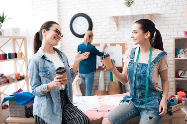 의류 공장에 세 여자입니다. 두 명은 커피 얘기 하 고 웃 고 마시고. — 스톡 사진