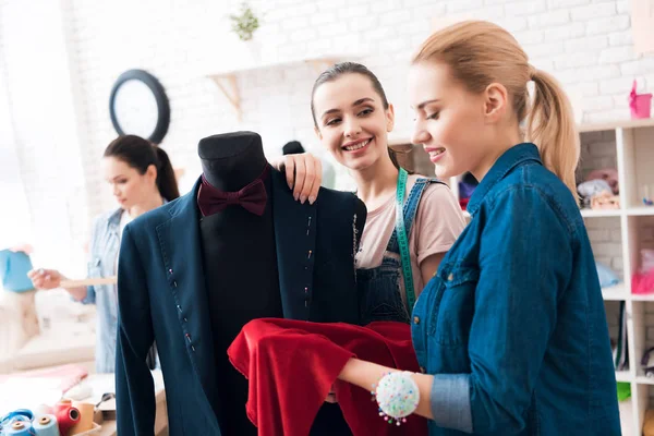 Tres chicas en la fábrica de ropa. Están discutiendo el diseño para la chaqueta del traje nuevo . —  Fotos de Stock