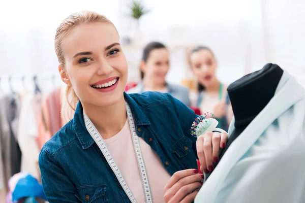 Drie meisjes in kledingstuk fabriek. Een van hen is het meten van nieuwe jurk. — Stockfoto