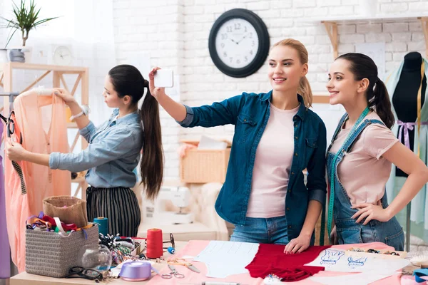 Three girls at garment factory. They are doing selfie on phone. — Stock Photo, Image