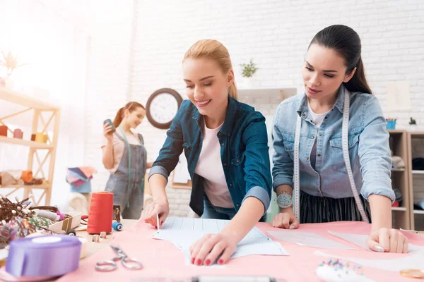 Three women at garment factory. One of them is making cut-out for new dress. — Stock Photo, Image