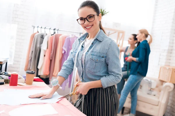 Três raparigas na fábrica de roupas. Um deles está fazendo cut-out para vestido novo . — Fotografia de Stock