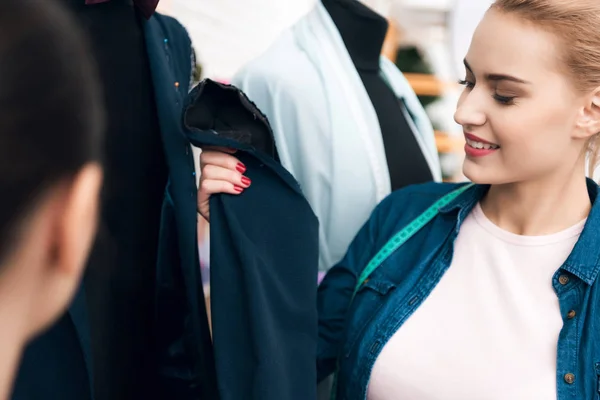 Two women at garment factory desining new man suit jacket.