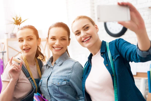 Três raparigas na fábrica de roupas. Eles estão tomando selfie desining vestido novo . — Fotografia de Stock
