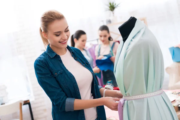 Tres chicas en la fábrica de ropa. Uno de ellos está midiendo vestido nuevo . —  Fotos de Stock