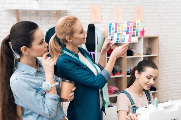 Three women at garment factory. They are looking at color patterns for new dress. — Stock Photo, Image