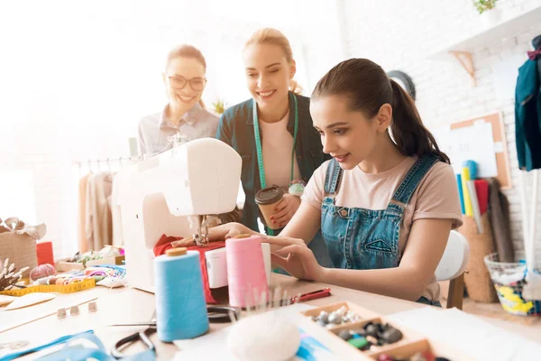Three women at garment factory. One of them is sewing new dress. — Stock Photo, Image