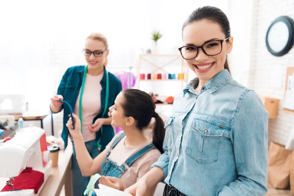 Drie vrouwen in kledingstuk fabriek. Zij kiezen voor ritsen voor de jurk. — Stockfoto