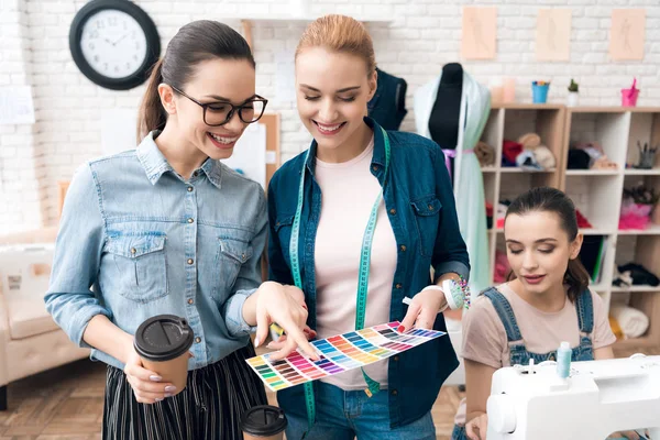 Three women at garment factory. They are looking at color patterns for new dress. — Stock Photo, Image