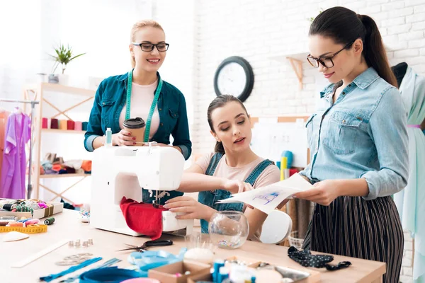 Three women at garment factory. One of them showing blueprint. — Stock Photo, Image