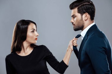 Siyah elbiseli güzel esmer kadın şık bir adam kravat tarafından tutuyor.