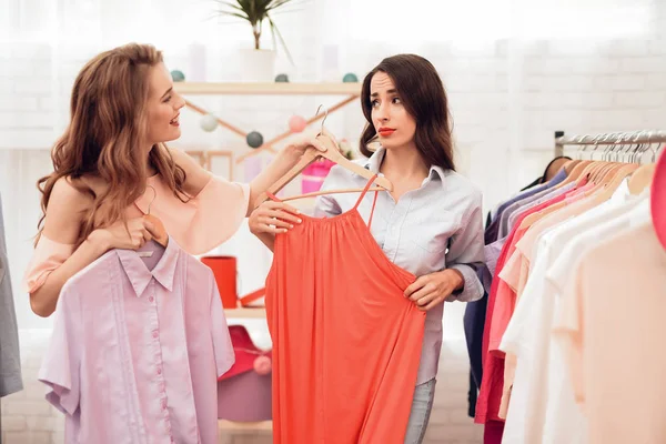 Dos chicas jóvenes de compras. Las niñas eligen la ropa en la tienda. Chicas en la sala de exposición . —  Fotos de Stock