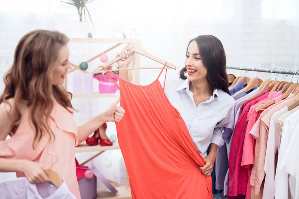 Dos chicas jóvenes de compras. Las niñas eligen la ropa en la tienda. Chicas en la sala de exposición . —  Fotos de Stock