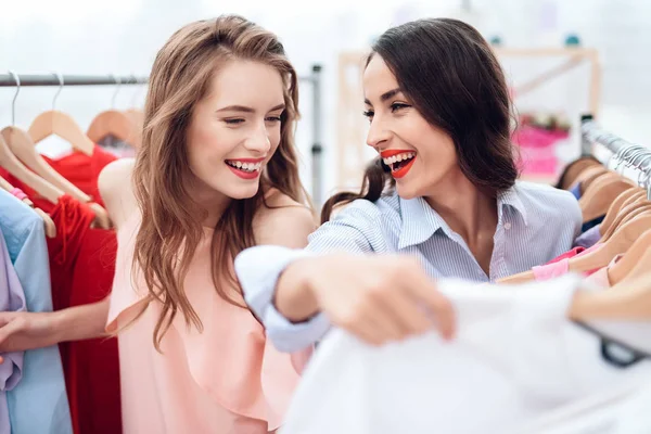 Dos chicas jóvenes de compras. Las niñas eligen la ropa en la tienda. Chicas en la sala de exposición . —  Fotos de Stock