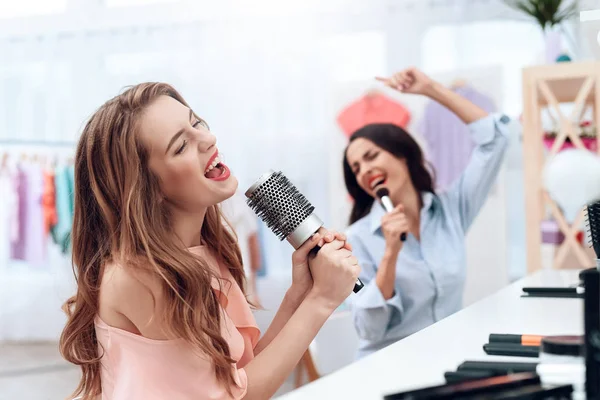 Girls are having fun in the showroom. Girls sing and hold a comb in their hands. — Stock Photo, Image