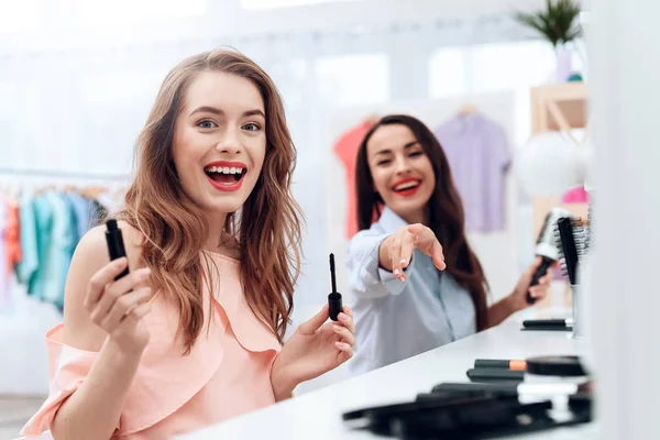 Girls do makeup in the showroom. Two beautiful girls have fun and smile. — Stock Photo, Image