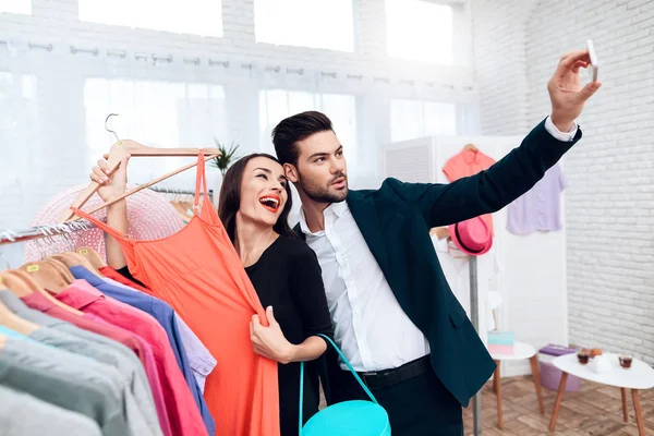 Mooi meisje in een jurk en een aantrekkelijke man in pak winkelt. Ze zijn in een lichte showroom. — Stockfoto