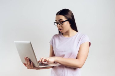 Genç kız telefonda konuşurken laptop yazmakta olduğunu. Beyaz arka plan üzerinde izole. Stüdyo portre.