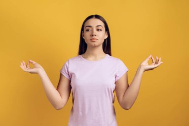 Genç sakin kız meditasyon, Zen alıyorum. Sarı arka plan üzerinde izole. Stüdyo portre.