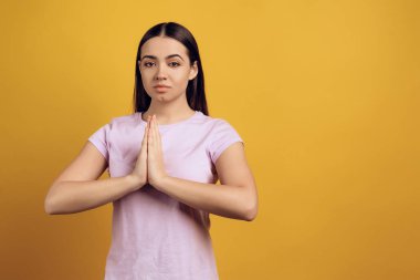 Genç sakin kız meditasyon, Zen alıyorum. Sarı arka plan üzerinde izole. Stüdyo portre.