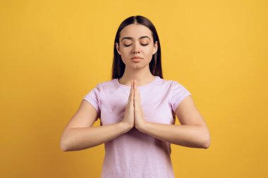 Genç sakin kız meditasyon, Zen alıyorum. Sarı arka plan üzerinde izole. Stüdyo portre.