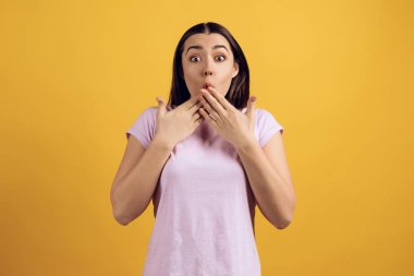 Pembe tshirt sürpriz genç kız portresi. Teen duygular. Sarı arka plan üzerinde izole.