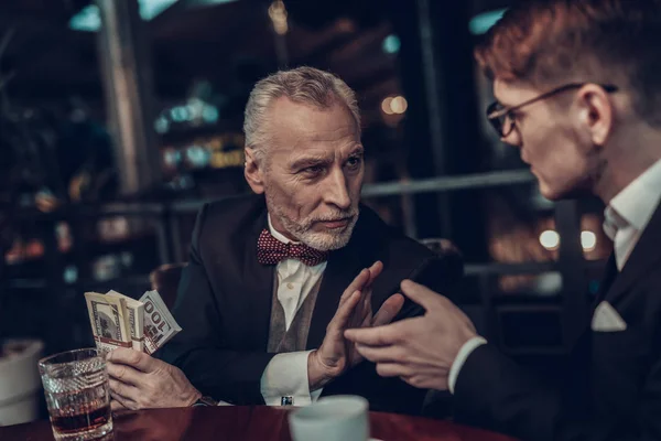 Businessman Using Laptop. Old Businessman . Man is Wearing in Black Suit. Experienced Entrepreneur. Strict Man. glass on table. Business Meeting. look at each other. expectation. extends hand