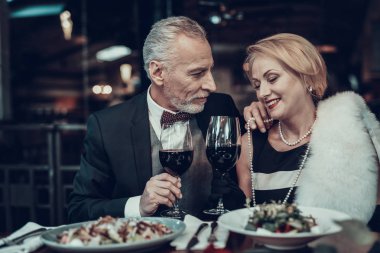 İş kadını ve iş adamı. Eski iş adamları. Başarılı yaşlılar. Birlikte sakin ol. Romantik toplantısı, zengin insanlar. Restoranda oturan bir çift. Lüks hayat. Birbirlerine bakıyorlar. gülümseyen kadın