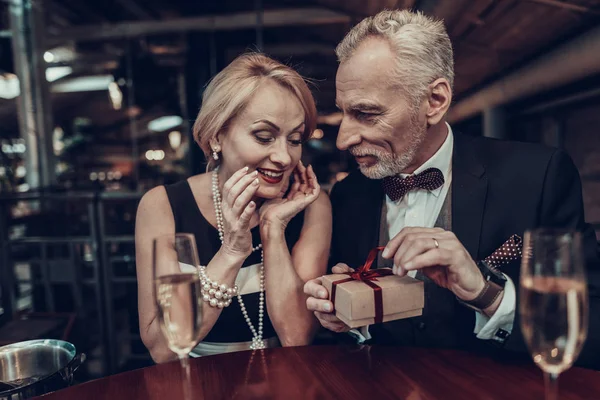 Businesswoman and Businessman . Old Business People .Successful Old People. Relax together. Romantic Meeting, Rich People. Couple Resting in Restaurant. gives gift to Woman. Woman is intrigued
