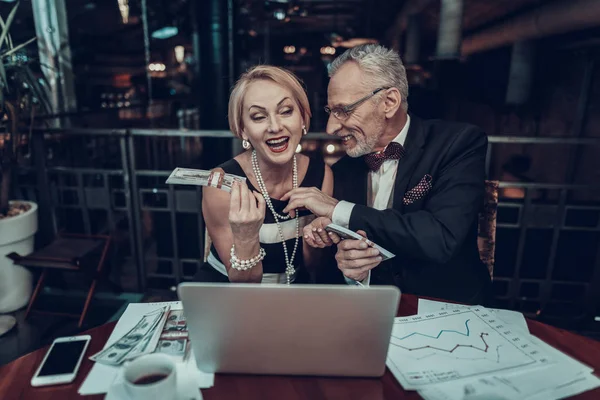 Businesswoman and Businessman . Old Business People . Experienced Entrepreneur. Working Late. Successful Old People. Sits in Office. holding stack of money. smiling People. touches Woman