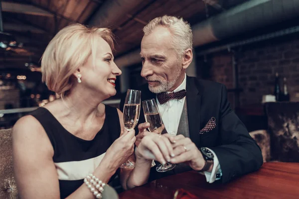 Businesswoman and Businessman . Old Business People .Successful Old People. Relax together. Romantic Meeting, Rich People. Couple Resting in Restaurant. look at each other. holding champagne glasses