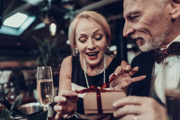 Businesswoman and Businessman . Old Business People .Successful Old People. Relax together. Romantic Meeting, Rich People. Couple Resting in Restaurant. Woman opens gift. cropped photo