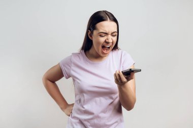 Genç kız telefonda konuşurken çığlık. Hoş olmayan konuşma kavramı. Beyaz arka plan üzerinde izole.