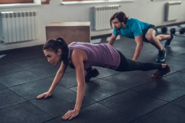 Kız menekşe T gömlek. Training Day. Fitness Kulübü. Sağlıklı bir yaşam tarzı. Güçlü atlet. Aktif tatiller. CrossFit kavramı. Spor salonu zemin kaynıyor. Rahat spor giyim. Kadın gücü.