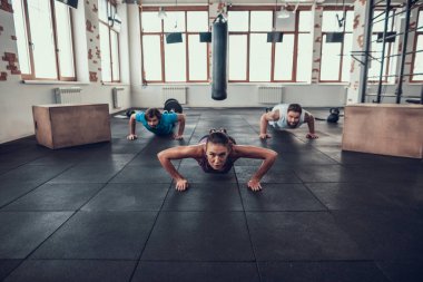 Erkek ve kadının yapması Push Ups. Training Day. Fitness Kulübü. Sağlıklı bir yaşam tarzı. Güçlü atlet. Aktif tatiller. CrossFit kavramı. Parlak spor salonu. Rahat spor giyim. Triceps kasları.