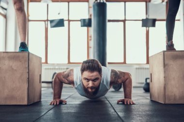 Sportif adam yapıyor iki sporcular arasında Ups itin. Training Day. Fitness Kulübü. Sağlıklı bir yaşam tarzı. Aktif tatiller. CrossFit kavramı. Parlak spor salonu. Rahat spor giyim. Egzersizleri tekrarlayın.