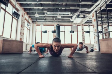 Erkek ve kadının yapması Push Ups. Training Day. Fitness Kulübü. Sağlıklı bir yaşam tarzı. Güçlü atlet. Aktif tatiller. CrossFit kavramı. Parlak spor salonu. Rahat spor giyim. Triceps kasları.