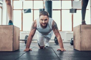 Sportif adam yapıyor iki sporcular arasında Ups itin. Training Day. Fitness Kulübü. Sağlıklı bir yaşam tarzı. Aktif tatiller. CrossFit kavramı. Parlak spor salonu. Rahat spor giyim. Egzersizleri tekrarlayın.