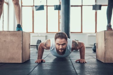 Sportif adam yapıyor iki sporcular arasında Ups itin. Training Day. Fitness Kulübü. Sağlıklı bir yaşam tarzı. Aktif tatiller. CrossFit kavramı. Parlak spor salonu. Rahat spor giyim. Egzersizleri tekrarlayın.