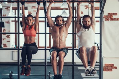 Yatay çubuk boğulan bir bacağı olan sporcular dayan. Training Day. Fitness Kulübü. Sağlıklı bir yaşam tarzı. Güçlü insanlar. Aktif tatiller. CrossFit kavramı. Parlak spor salonu. Basın çalışmaları.