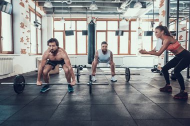 Halter kaldırma spor salonunda iki adam. Destekleyici kız. Koç ile Training Day. Fitness Kulübü. Sağlıklı bir yaşam tarzı. Güçlü atlet. Aktif tatiller. CrossFit kavramı. Rahat spor giyim.